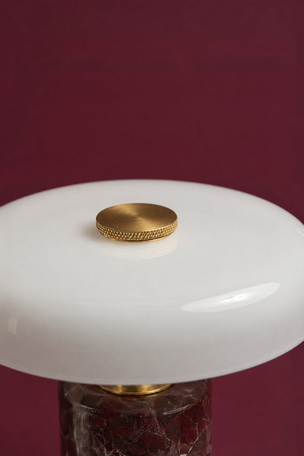 Close-up of the knurled brass touch-dimmer cap in the centre of the Columba lamp's white opal glass disc.