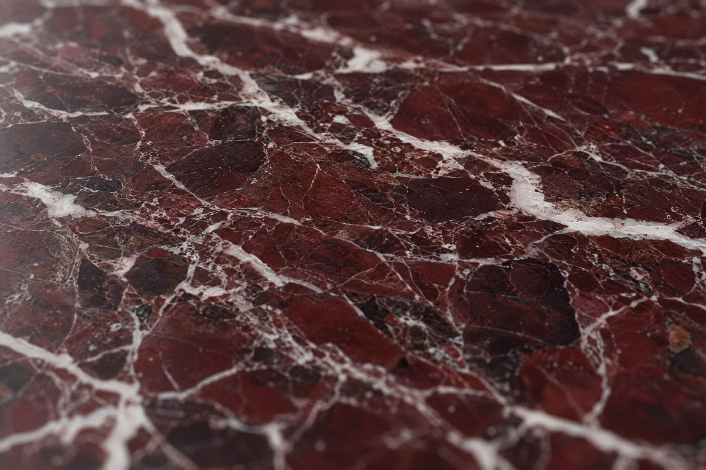 Rosso Levanto marble, close: a deep wine-red ground broken by a network of crisp white veins, polished.